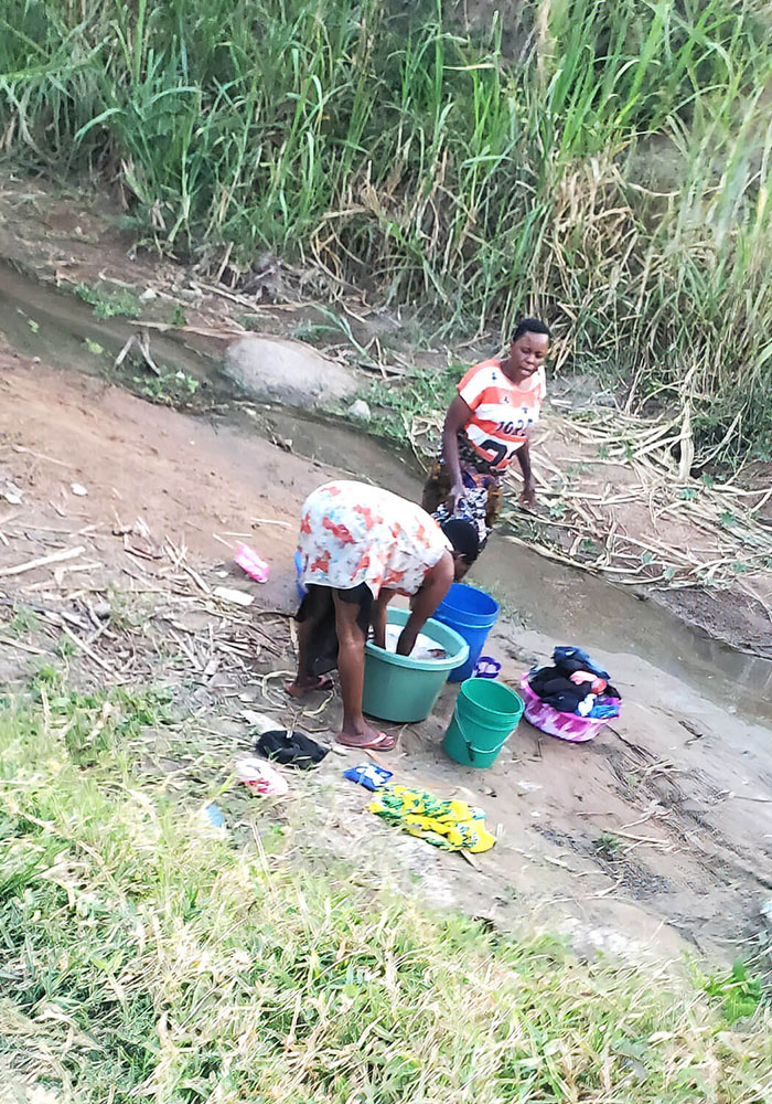 Two women washing clothes near a stream
