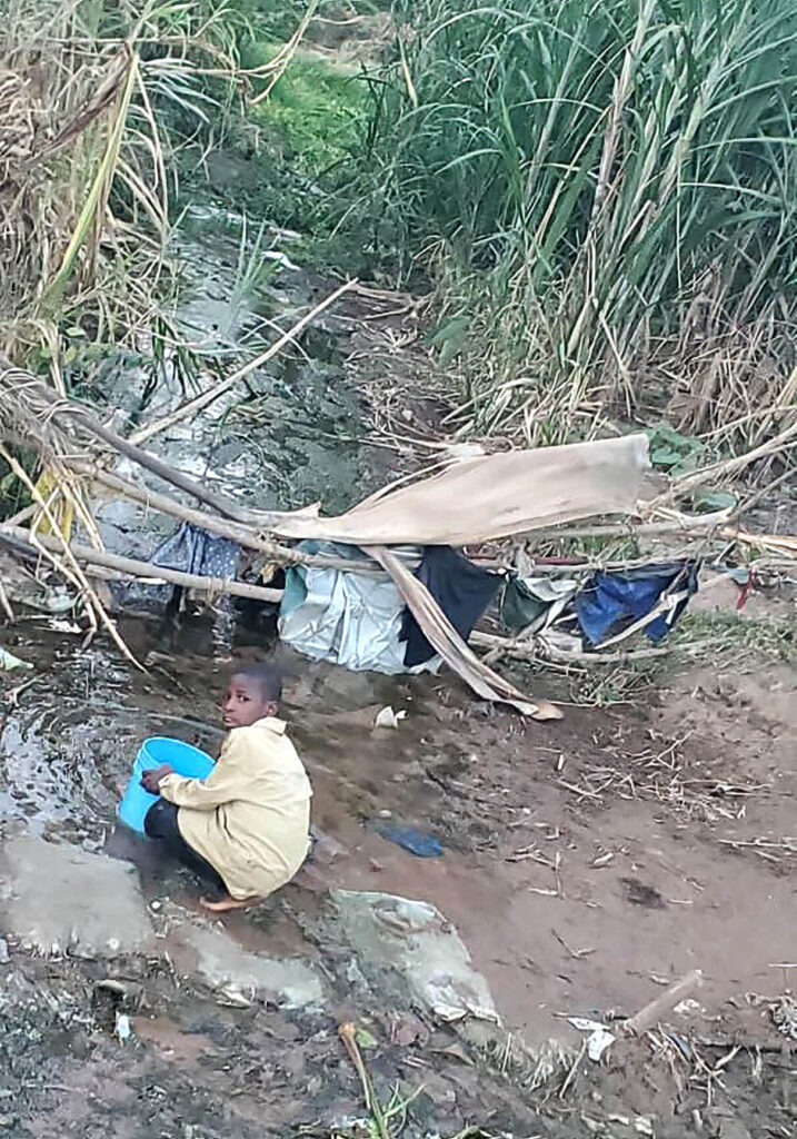 Child collecting water from a polluted stream in a rural community